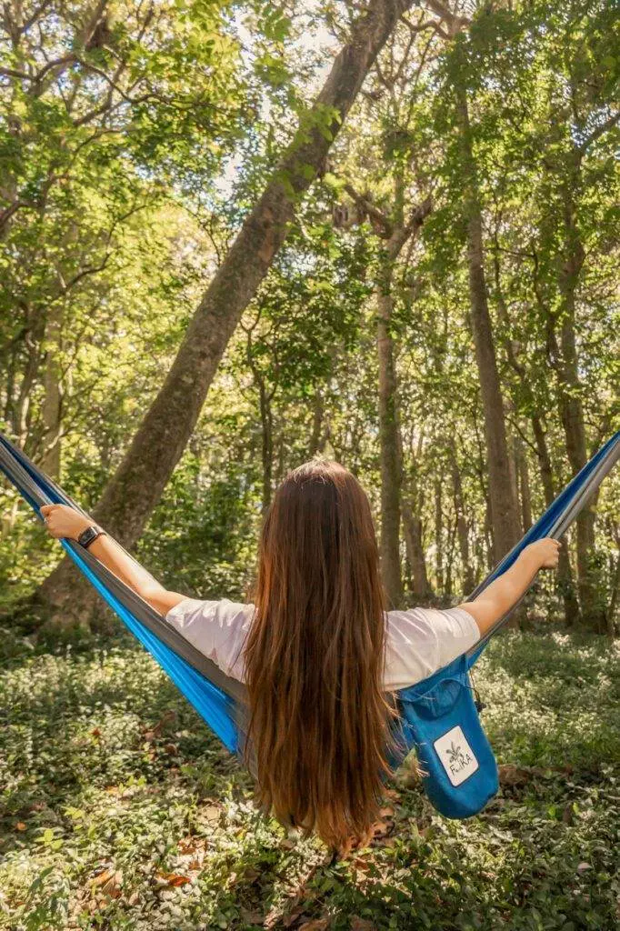 girl with long hair sitting in blue hammock