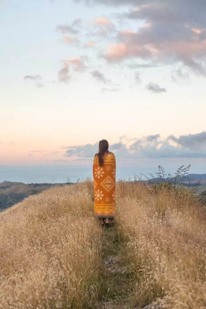 girl wrapped in throw overlooking newzealand landscape